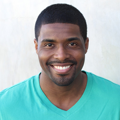 A man and woman are smiling and embracing each other outdoors.