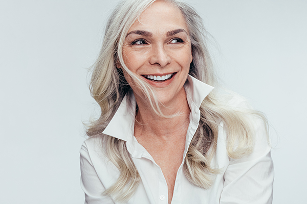 A woman with short hair smiling at the camera, wearing a white shirt.